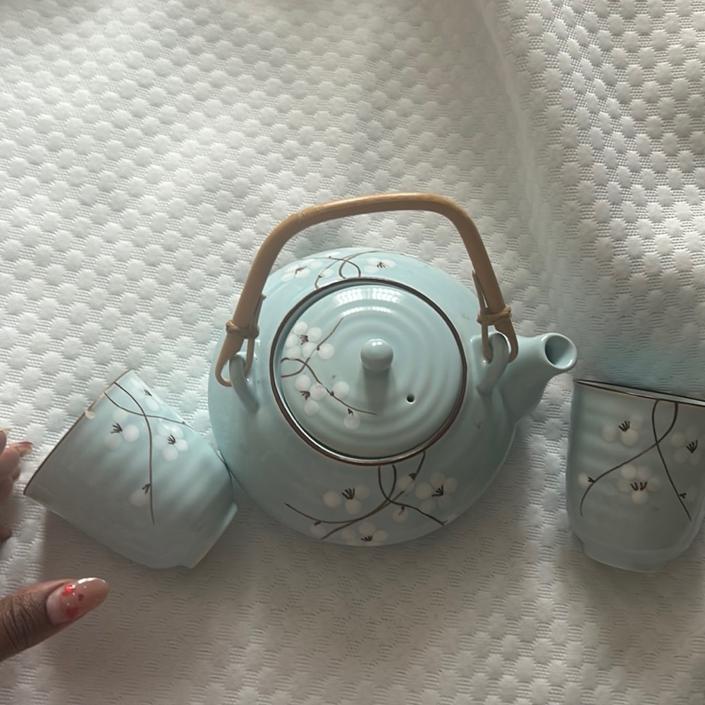 Light blue teapot with flowers design in white with tan accent bamboo handle